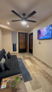 a living room with a black couch and a ceiling fan at KASA in Tulum