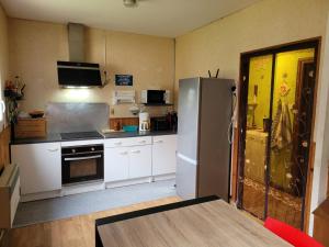 eine Küche mit weißen Schränken und einem Kühlschrank in der Unterkunft Gîte Espace et Montagne in Aragnouet