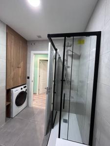 a bathroom with a shower and a washing machine at Vistas Sobia San Martín de teverga in San Martín