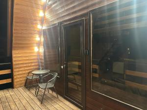 a balcony with two chairs and a table and a glass door at Tuyo cottages Gudauri in Gudauri