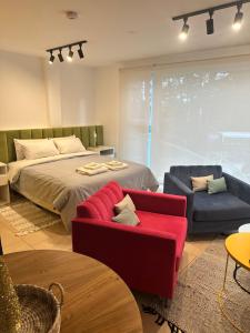 1 dormitorio con cama, sofá rojo y sillas en Aurora, en Ushuaia