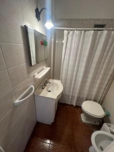 a white bathroom with a sink and a toilet at Departamento Playa Grande in Mar del Plata