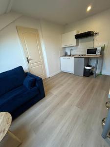 a living room with a blue couch and a kitchen at Parfait F1, Entrée du Havre #10 in Le Havre