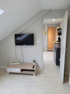 a living room with a table and a tv on the wall at Parfait F1, Entrée du Havre #11 in Le Havre