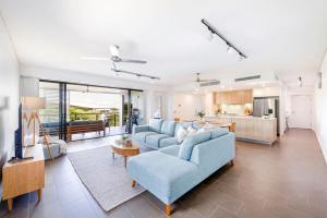 a living room with a blue couch and a kitchen at Waterfront Bliss - Explore Darwin's Premier Location in Darwin