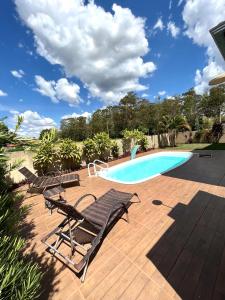 a swimming pool with two chaise lounges next to a swimming pool at Thermas aguas de santa barbara in Santa Bárbara do Rio Pardo