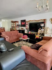a living room with orange couches and a tv at Ponto do Paraíso - Quarto inteiro em apartamento compartilhado in Fortaleza
