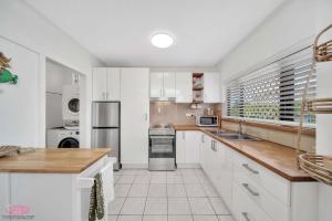 eine Küche mit weißen Schränken und weißen Geräten in der Unterkunft Kamboola 5 Beach Breeze in South Mission Beach