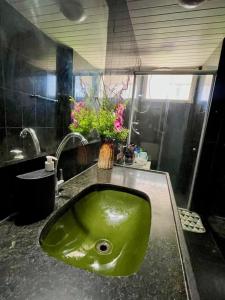 a green sink in a bathroom with flowers on it at Ponto do Paraíso - Quarto inteiro em apartamento compartilhado in Fortaleza