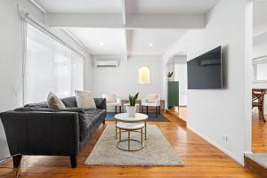 a living room with a black couch and a table at The Cosy Haven in Mont Albert