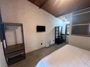 a bedroom with a bed and a tv on the wall at Cabanas All Black in Monte Verde