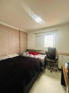 Un dormitorio con una cama, una silla y una ventana en Apartamento Guaraci, en Praia Grande