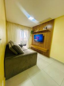 Una sala de estar con un sofá y un televisor. en Apartamento Guaraci, en Praia Grande