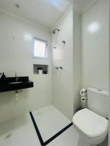 Un baño blanco con inodoro y lavabo. en Apartamento Guaraci, en Praia Grande
