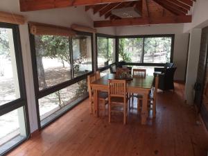 Un comedor con mesa y sillas y ventanas. en La Almenara Lodge, en Villa General Belgrano