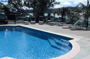 a blue swimming pool with chairs at Acacia Lodge Motel in Mangonui