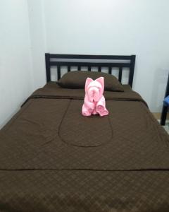 un peluche rosa è seduto su un letto di ÀCER guesthouse a Petchaburi