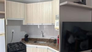 a kitchen with a sink and a stove at Espaçoso 1 d perto do mar com vaga in Capão da Canoa