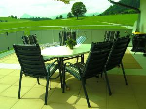 een tafel en stoelen op een balkon met uitzicht op een veld bij Pfandlhof in Walchsee