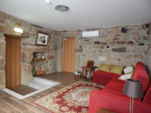a living room with a red couch and a stone wall at Casa de Campo das Sécias in Vilas Boas