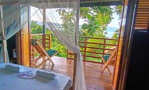 a room with a bed and a balcony with a view at The View - Jungle Lodges - Port Barton in San Vicente