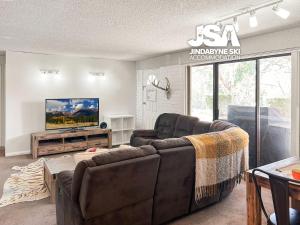 a living room with two couches and a tv at Silvers 1 in Jindabyne