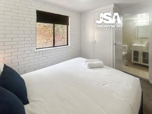 a bedroom with a large white bed with a window at Silvers 1 in Jindabyne