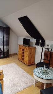 ein Wohnzimmer im Dachgeschoss mit Fernseher und Tisch in der Unterkunft Chez Maurizio in Villemanoche