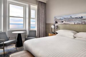 a hotel room with a bed and chairs and a window at Bournemouth Highcliff Marriott Hotel in Bournemouth