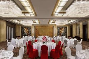 a banquet room with white tables and red chairs at Courtyard by Marriott Suzhou in Suzhou
