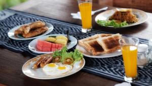 a table with plates of breakfast foods and orange juice at Kubu Damai Guest House in Jatiluwih