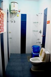 a bathroom with a toilet and a blue bucket at Holidayincoorg Royal Mansion in Madikeri