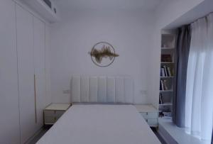 a white bedroom with a bed and a book shelf at Cloud&Sea Inn in Shenzhen