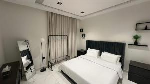 a bedroom with a large white bed and a chair at Cozy Stylish Apartment الياسمين شمال الرياض in Riyadh