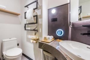 a bathroom with a white toilet and a sink at Cozylife Hotel Canal in Hangzhou