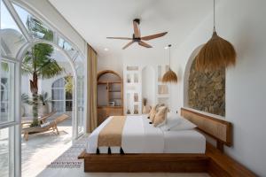 een slaapkamer met een bed en een plafondventilator bij Casa Mana Ubud in Ubud