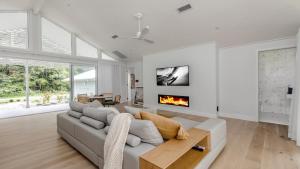 un salon avec un canapé et une cheminée dans l'établissement Resort Style Living With Pool, Tennis Court and Beach, à Avoca Beach