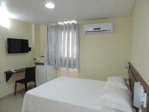 a bedroom with a bed and a desk and a television at Hotel Sandis Mirante in Santarém