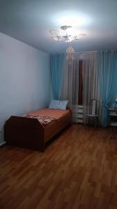 een slaapkamer met een bed en blauwe gordijnen bij Run İn Joy Hostel in Qostanaj