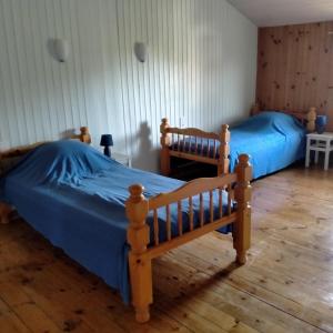 two beds in a bedroom with blue sheets at Les volets rouges in Saint-Clément-de-Régnat