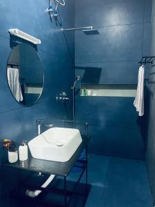 une salle de bain bleue avec un lavabo et un miroir dans l'établissement Munroe Plackal Heritage, à Munroe Island