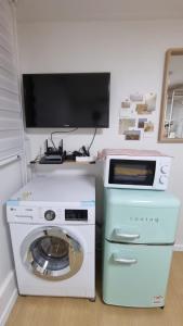 a washing machine and a tv in a room at The Happy Stay in Uijeongbu
