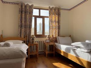twee eenpersoonsbedden in een kamer met een raam bij Old Bukhara Terrace with Panoramic view of the old city in Bukhara