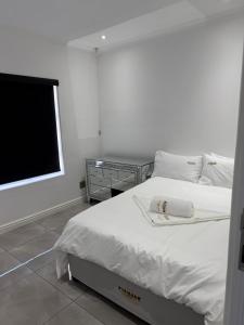 una camera da letto con un letto bianco e una televisione di The Zebra a Gqeberha