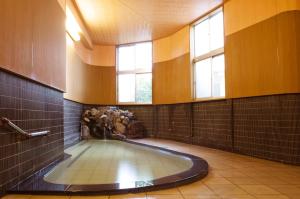 a bathroom with a hot tub in a room with windows at KKR Suwakoso in Suwa