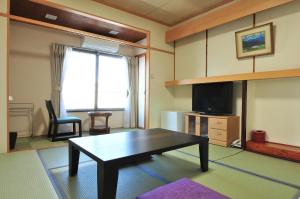 a living room with a coffee table and a tv at KKR Suwakoso in Suwa