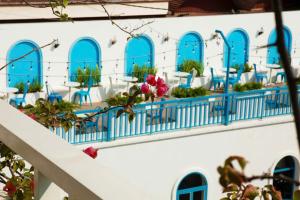 Un edificio blanco con ventanas azules, mesas y sillas. en Hương Sen Hotel MC - by BAY LUXURY, en Mộc Châu