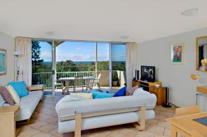 sala de estar con sofás blancos y balcón en Horizons At Peregian, en Peregian Beach