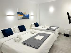 two beds in a white room with towels on them at Central Suites Aegina 4 in Aegina Town