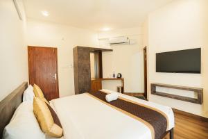 ein Schlafzimmer mit einem Bett und einem Flachbildfernseher in der Unterkunft Sreeja Myst in Athirappilly